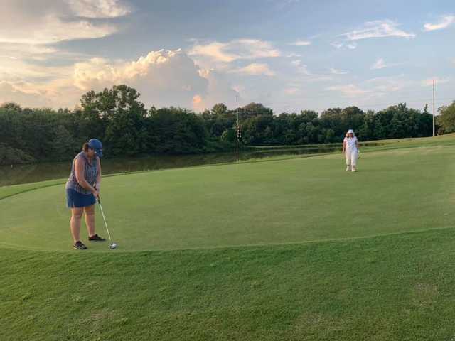 A view of a green with water in background at River Birch Golf Club.