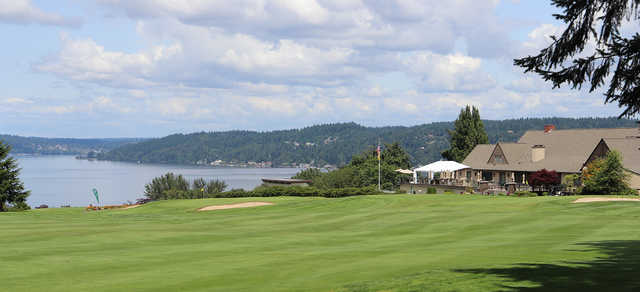 A view of two greens with water in background and the clubhouse on the right side at Sand Point Country Club.