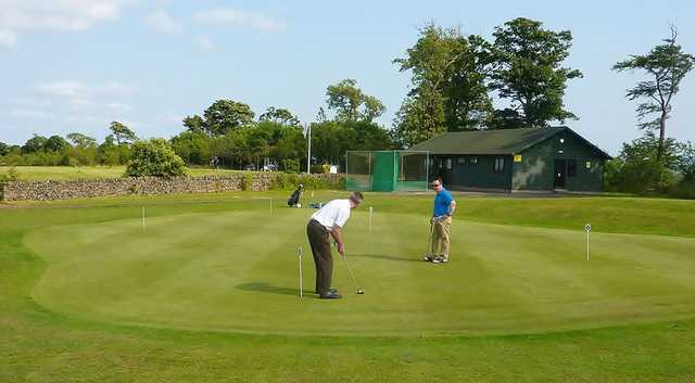 View of the putting green and clubhouse at Oatridge Golf Course.