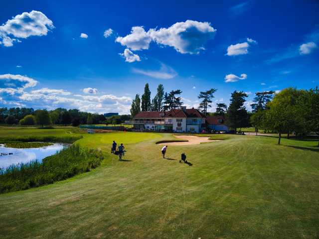 A sunny day view of a green and the clubhouse in background at Woolston Manor Golf & Country Club.
