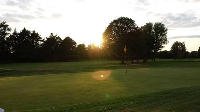 A sunny day view of a green at Chorlton-cum-Hardy Golf Club.