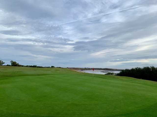 A view of a green with water in background at Alnmouth Golf Club.