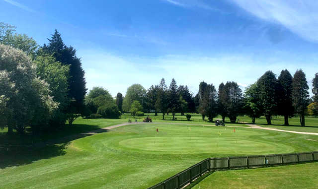 A sunny day view of a the practice area and a green at Cricket St. Thomas Golf Club.