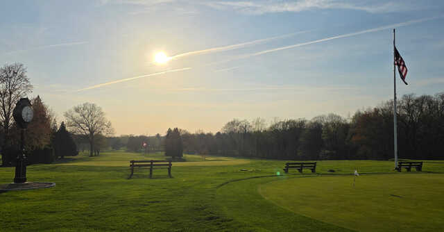 A sunset view of a green and the practice area at Race Brook Country Club.