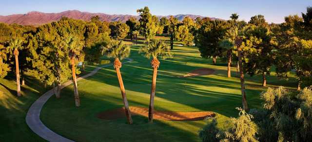 A sunset view of green #18 with a narrow road on the left at Red Course from Wigwam Resort