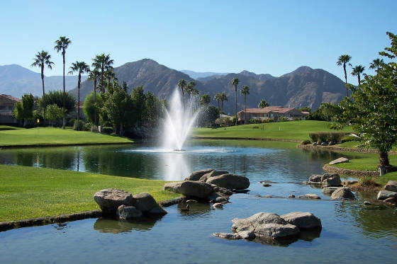 A view of green with water fountain in foreground at Palm Royale Country Club