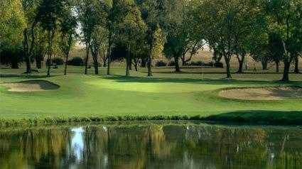 A view over the water of a green protected by bunkers at Campus Commons Golf Course