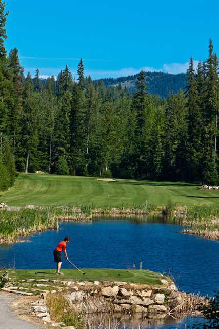 A view of a tee surrounded by water, fairway and green at Priest Lake Golf Club