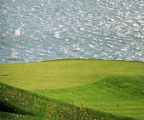 A view of the 6th green with water in background from Harbor Links at Sagamore Resort
