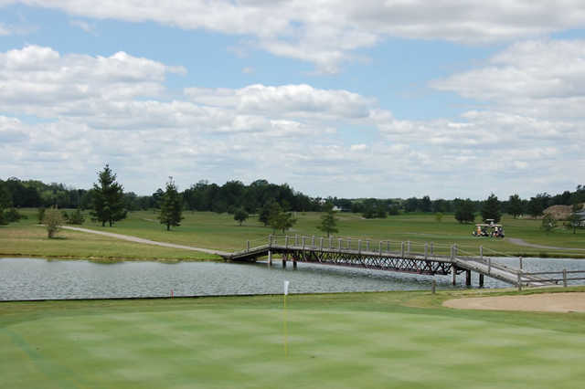 A view of a green with a bridge in the background at Holly Meadows Golf Course