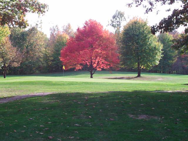 A view of a green guarded by fall red tree at English Hills Golf Course