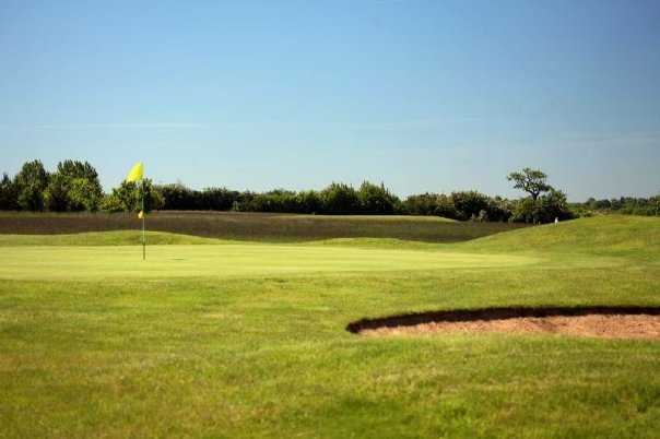 A sunny view of a green guarded by bunker at Championship Course from Great Hadham Golf Club