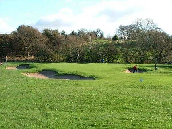 A view of the 15th green guarded by bunkers at Penwortham Golf Club