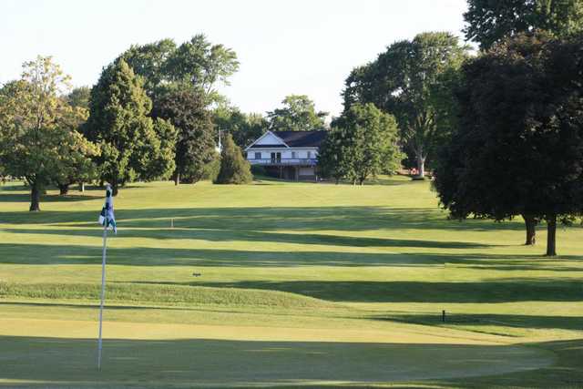 View of a green with clubhouse in the back at The Fields Golf Course