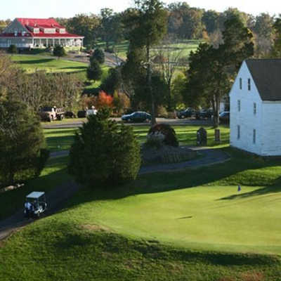 A sunny view of a green with the clubhouse in background at Meadows Farms Golf Course