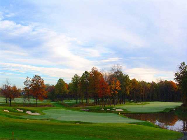 A fall view of a green flanked by sand traps and a pond at Thundering Waters Golf Club