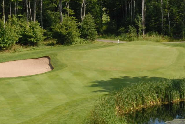 A view of a green guarded by a bunker and a pond at Wild Bluff Golf Course