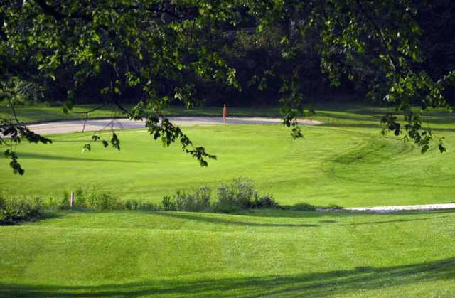 A view of a green guarded by an undulating bunker at Orangeville Golf Club