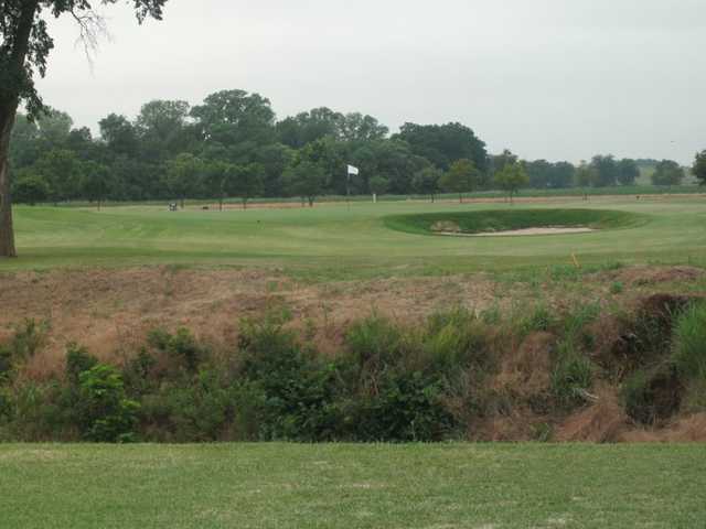 A view of a green guarded by a bunker at Riverside Golf Course
