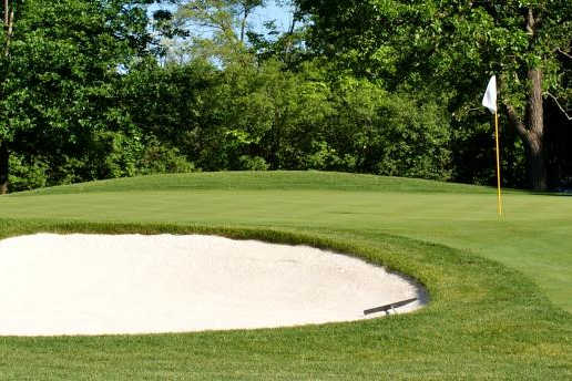 A view of a green guarded by a large bunker at Knollwood Club