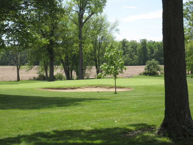 A sunny day view of a green protected by bunkers at Hickory Hills Golf Club