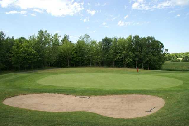 A view of a green protected by a large bunker at Baker National Golf Course