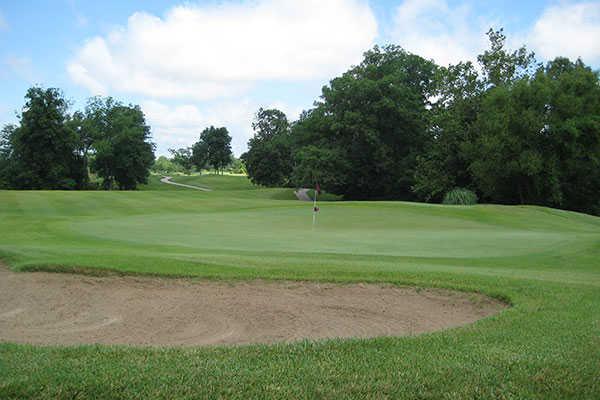 A view of a green protected by a bunker at Hickory Ridge Golf Center