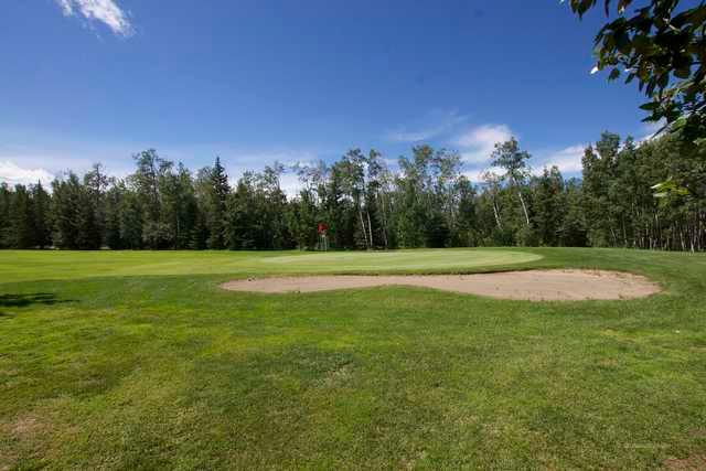 A view of a green protected by a bunker at Pipestone Golf Club
