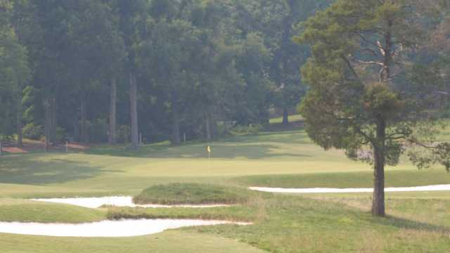 A view of a green protected by sand traps at Forest Oaks Country Club