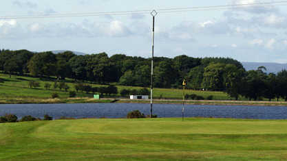 A view of a green with water in background at Fereneze Golf Club