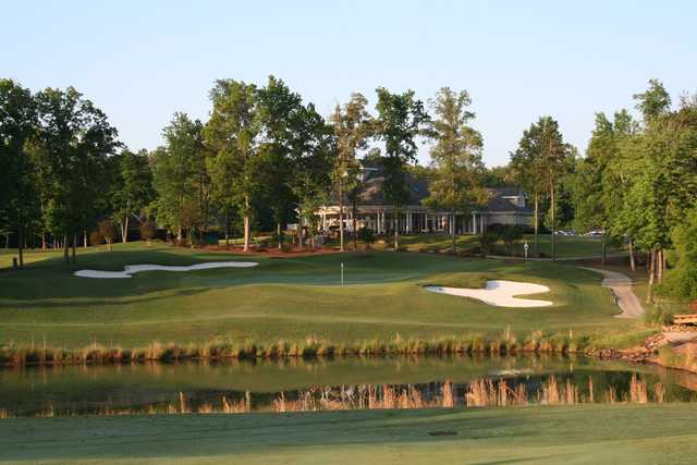 A view over the water of a green and the clubhouse in background at Olde Sycamore Golf Plantation