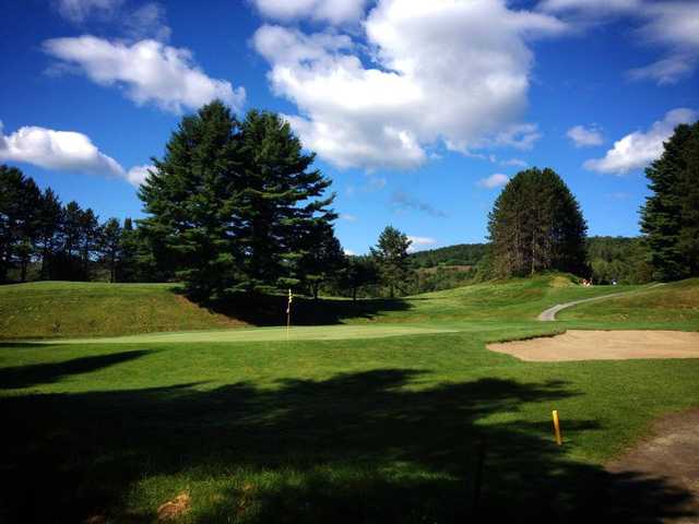 A view of a green protected by a bunker at St. Johnsbury Country Club