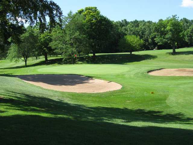 A sunny day view of a hole surrounded by sand traps at Reid Golf Course