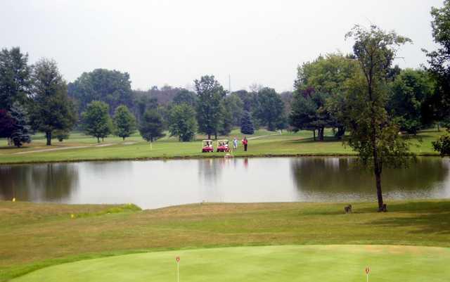 A view of green surrounded by water with two carts in  background at Reddeman Farms Golf Club
