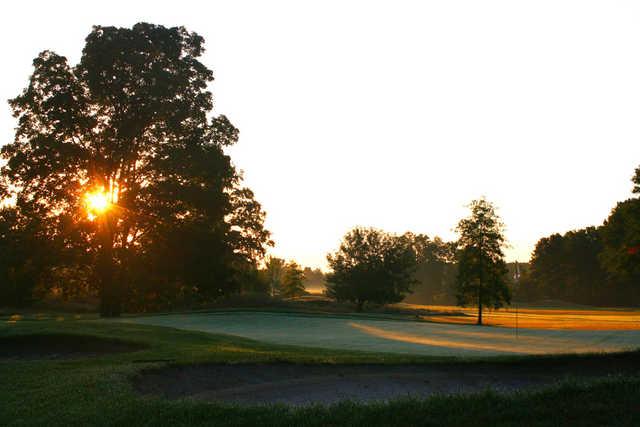 A sunset view of a green protected by bunkers at Brookshire Inn & Golf Club.