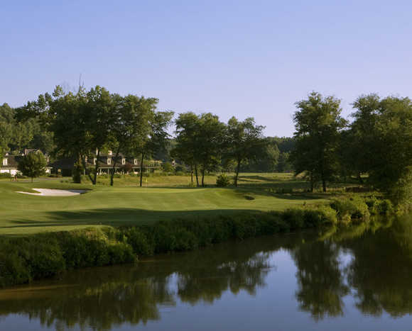 A view of a hole surrounded by water with the clubhouse in background at Achasta Golf Club