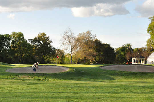 A view of a green guarded by sand traps at Haggin Oaks Golf Course