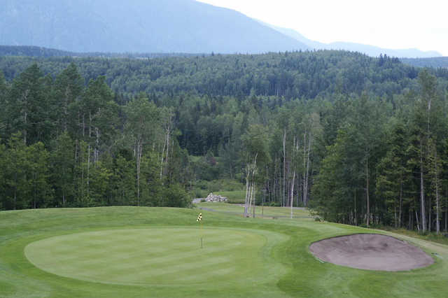 A view of a green protected by a bunker at Skeena Valley Golf and Country Club