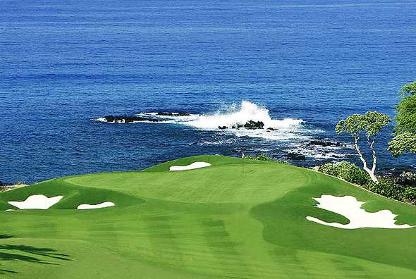 A view of a green with water in background at Mauna Kea Golf Course