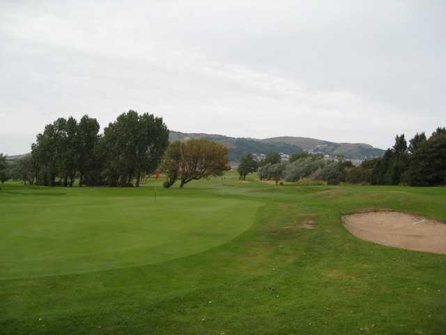 A scenic view of the 6th green and surrounding mountains at Llandudno Maesdu Golf Club