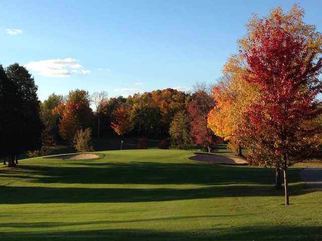 A fall day view of a green flanked by bunkers at Sugar Springs Golf Course