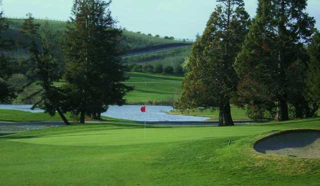 A view of green with bunker on the right and water in background at Bay View Golf Club.