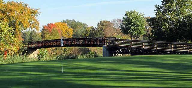 A view of a green with a bridge in background at Pine Hills Golf Club