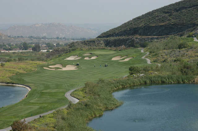 A view of green #10 surrounded by bunkers with water on the right at Oak Quarry Golf Club