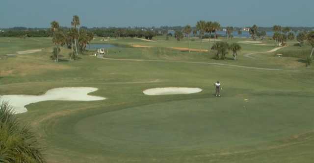 A view of a green protected by sand traps at Cocoa Beach Country Club with narrow road on the left