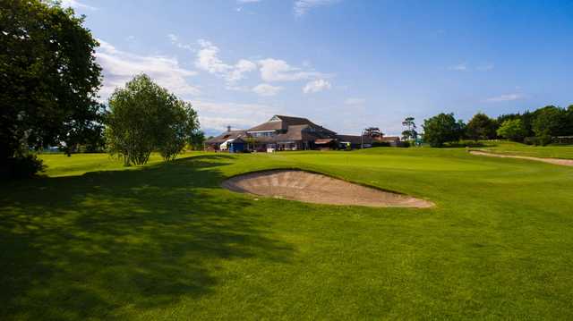 View of a green with the clubhouse in the background at Dudsbury Golf Club