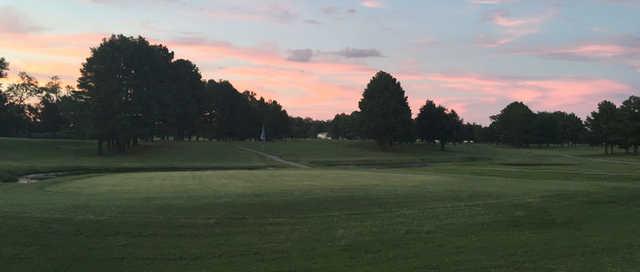 A sunset view of a green with water in background at Pine Lakes Golf Course.