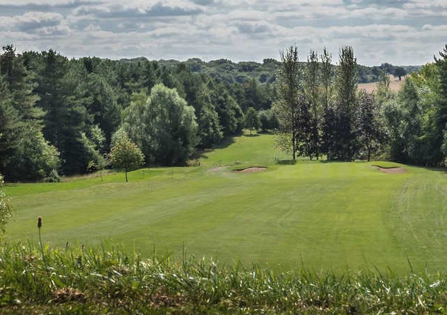 A sunny day view of a hole flanked by tricky bunkers at Priors Hall Golf Club.