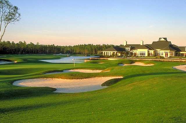 A view of a green protecteed by bunkers with clubhouse in background at St. Johns Golf & Country Club