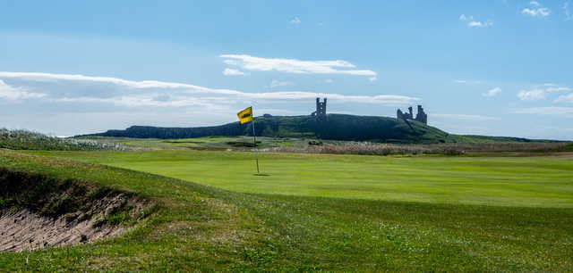 A sunny day view of a hole at Dunstanburgh Castle Golf Club.